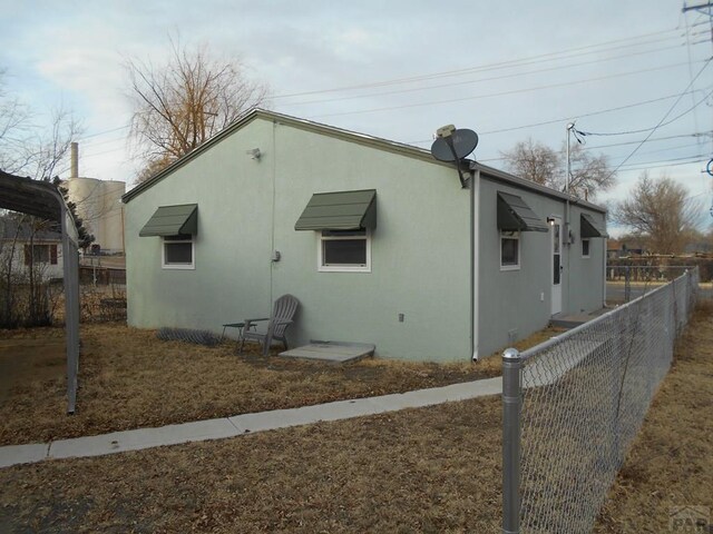 view of side of home featuring fence and stucco siding