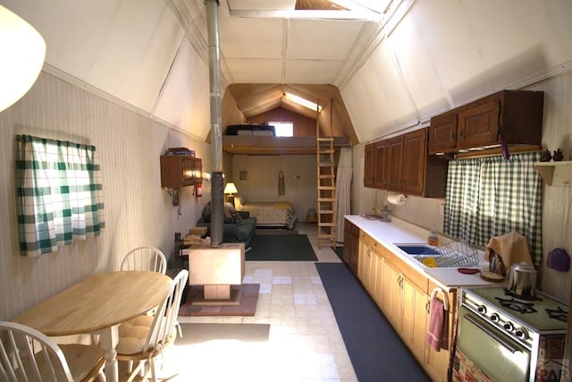 kitchen with a sink, vaulted ceiling, gas range, and light countertops