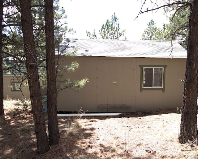 view of side of property featuring an outbuilding and roof with shingles