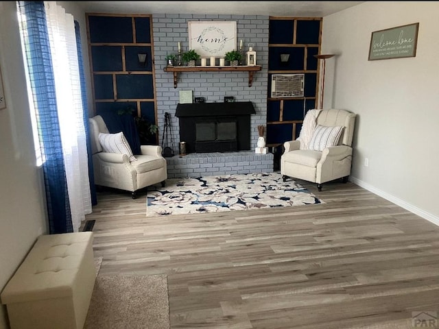 living area featuring baseboards, wood finished floors, and a fireplace