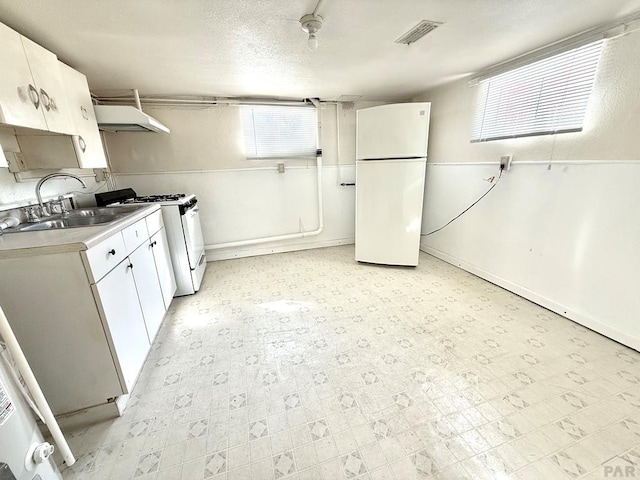 kitchen featuring under cabinet range hood, white appliances, white cabinetry, visible vents, and light floors