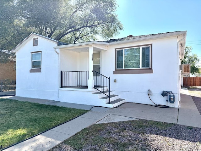 view of front of home with covered porch, a front lawn, and stucco siding