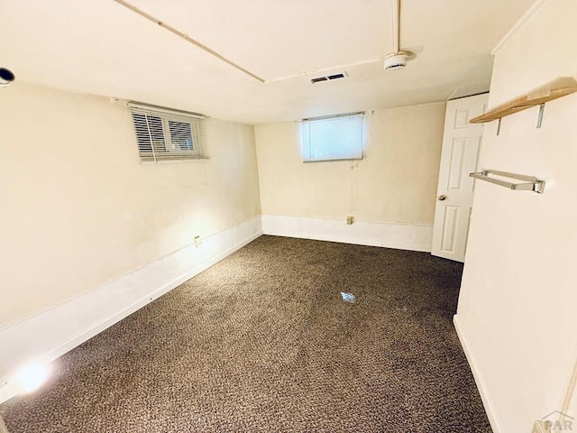 below grade area with visible vents, dark carpet, and baseboards