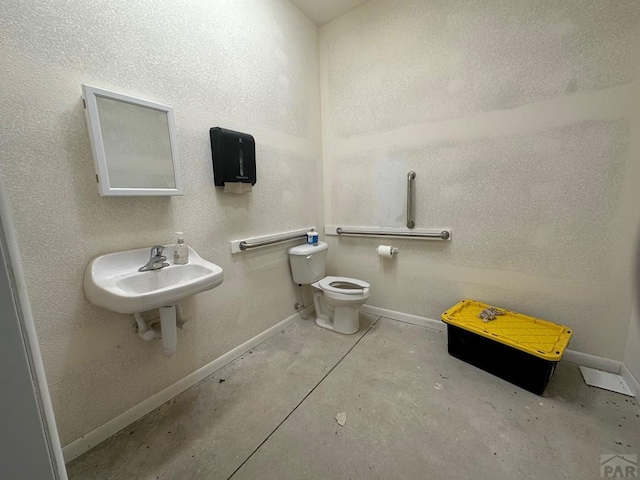 bathroom with toilet, concrete floors, baseboards, and a sink