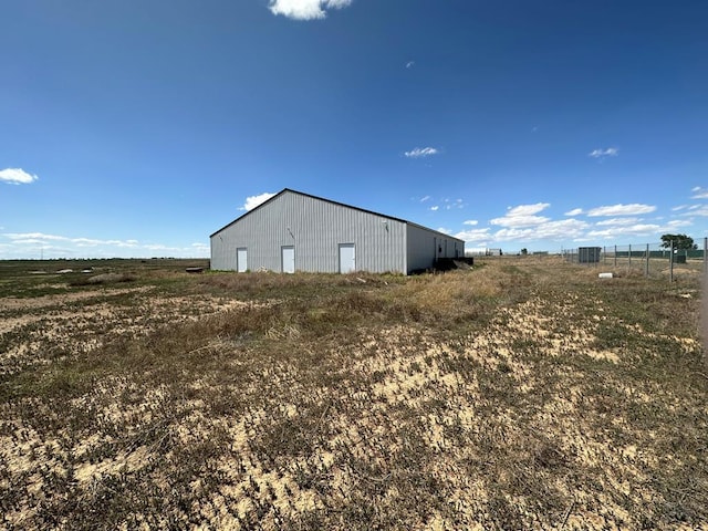 view of side of home featuring an outbuilding, a pole building, and a rural view