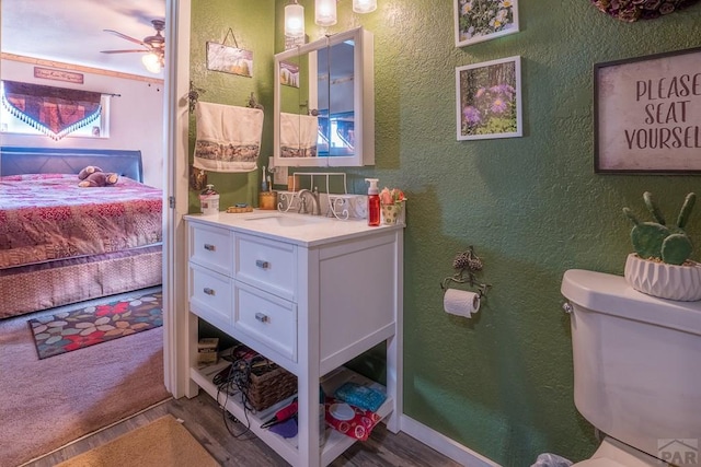 bathroom featuring toilet, wood finished floors, and a textured wall