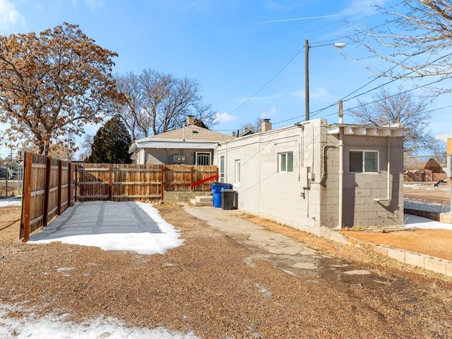 rear view of house featuring fence and concrete block siding