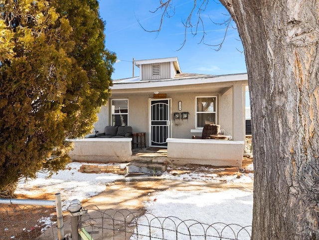 bungalow-style house with covered porch, a fenced front yard, a gate, and stucco siding