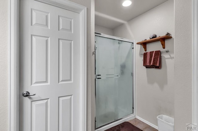 bathroom with a stall shower, tile patterned flooring, and baseboards