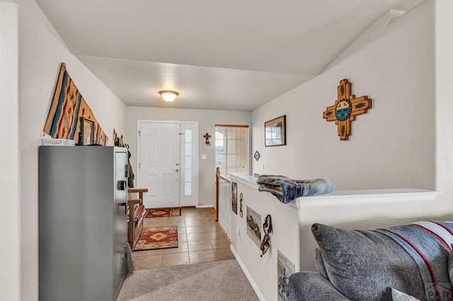 entrance foyer with light tile patterned floors, baseboards, and light colored carpet