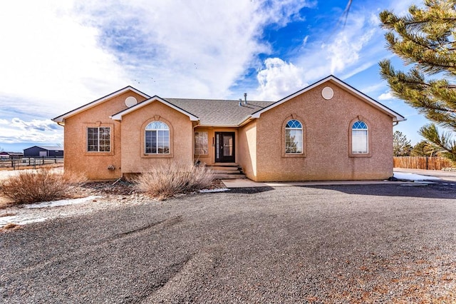 ranch-style house with fence and stucco siding