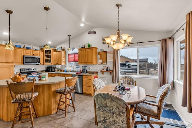 kitchen featuring lofted ceiling, light countertops, hanging light fixtures, appliances with stainless steel finishes, and glass insert cabinets