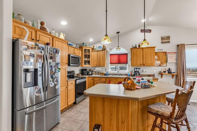 kitchen with light countertops, appliances with stainless steel finishes, glass insert cabinets, a kitchen island, and a kitchen breakfast bar