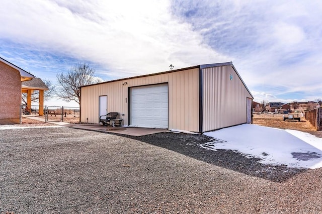 detached garage featuring gravel driveway and fence