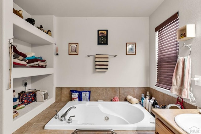 bathroom with a tub with jets, vanity, and tile patterned floors