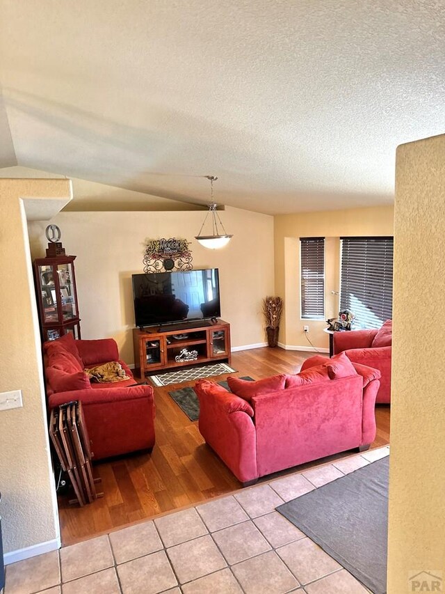 living area featuring light tile patterned flooring, a textured ceiling, and baseboards