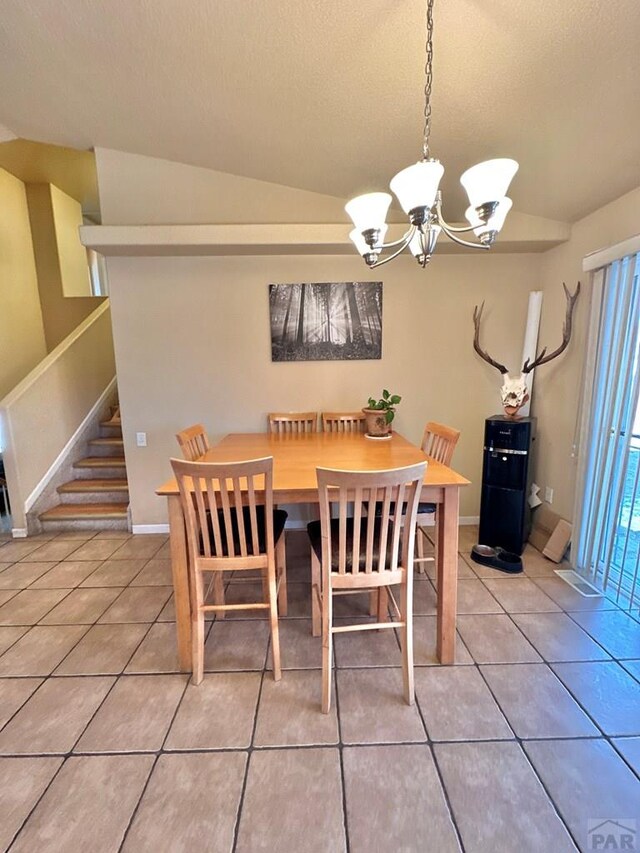 dining space featuring an inviting chandelier, a textured ceiling, tile patterned flooring, baseboards, and stairs