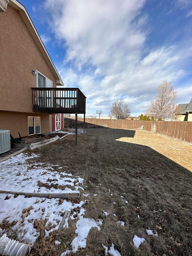 yard layered in snow with a fenced backyard, central AC, and a wooden deck