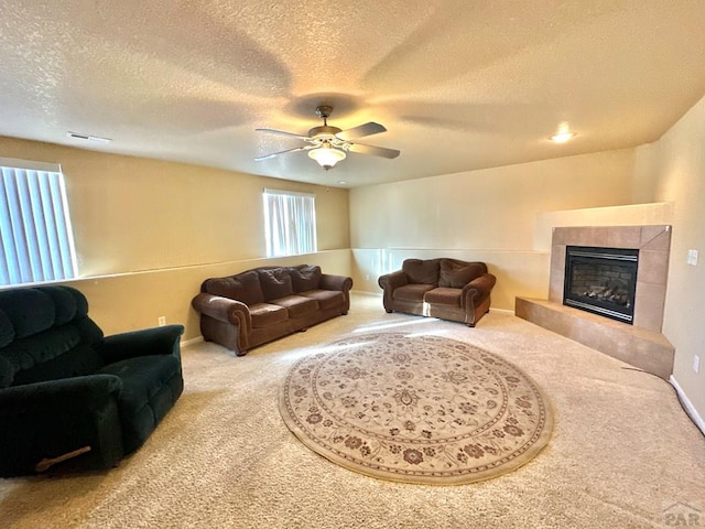 living area featuring a ceiling fan, carpet flooring, a fireplace, and a textured ceiling