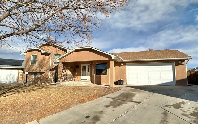 view of front of house with solar panels, concrete driveway, an attached garage, and stucco siding