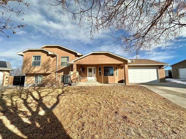 split level home featuring stucco siding, a porch, an attached garage, cooling unit, and driveway