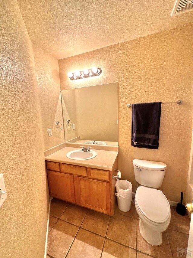 bathroom featuring visible vents, a textured wall, toilet, a textured ceiling, and vanity