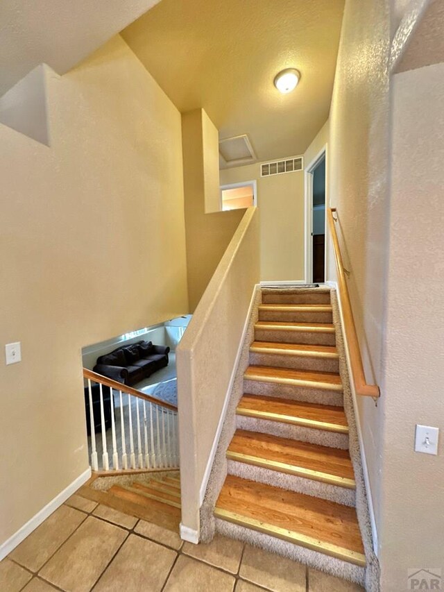 stairs featuring visible vents, baseboards, and tile patterned floors