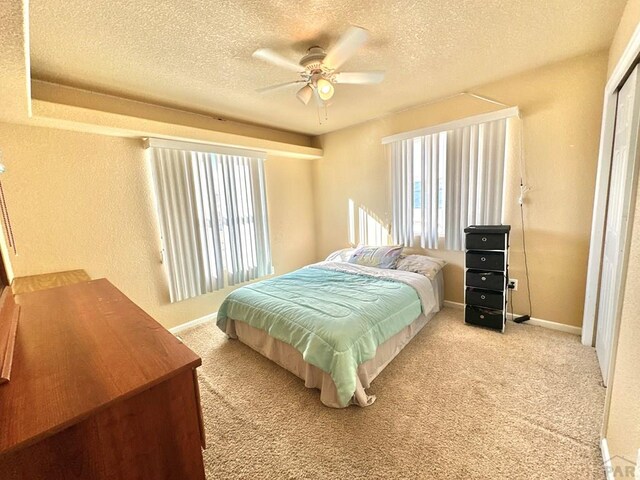 bedroom with light colored carpet, a textured ceiling, and multiple windows