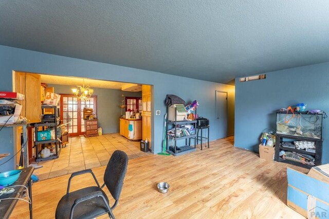 interior space featuring light wood-type flooring, a textured ceiling, and an inviting chandelier