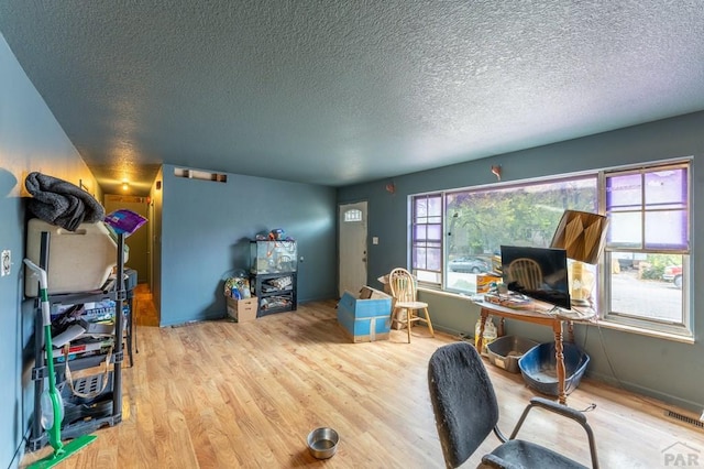 office featuring a textured ceiling, light wood finished floors, and visible vents