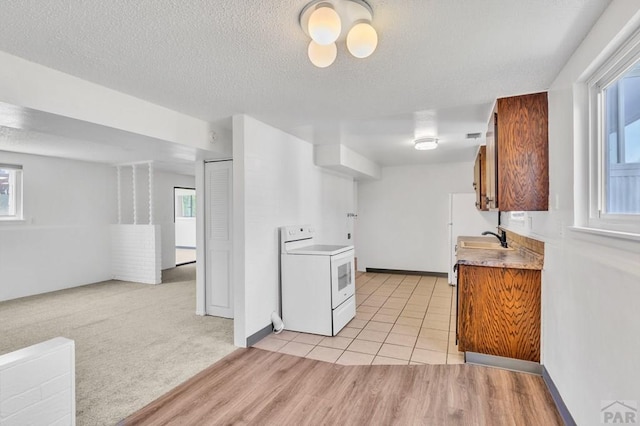 kitchen with white electric range oven, a sink, light countertops, a textured ceiling, and open floor plan