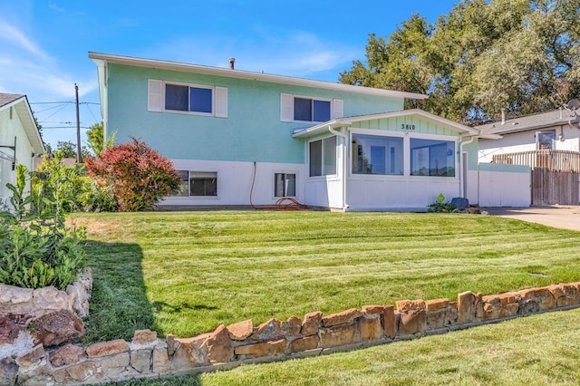 rear view of property with stucco siding, a lawn, and fence