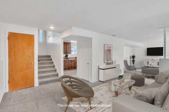 living room with stairs, a textured ceiling, and light carpet