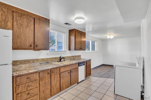 kitchen featuring light countertops, light tile patterned floors, white appliances, washer / clothes dryer, and a sink