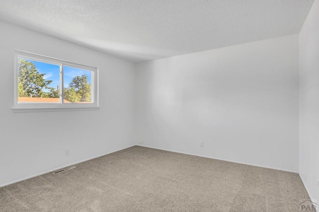 unfurnished room with visible vents, carpet flooring, and a textured ceiling