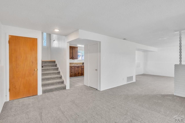 interior space with stairs, carpet flooring, visible vents, and a textured ceiling