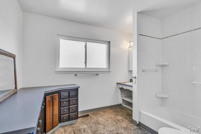 bathroom with shower / washtub combination, vanity, stone finish flooring, and baseboards