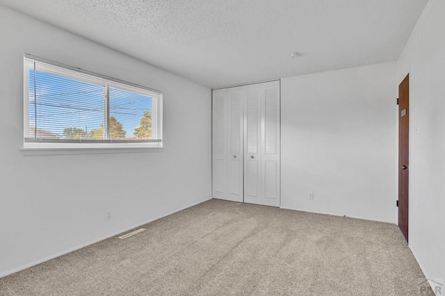 unfurnished bedroom with a closet, visible vents, carpet flooring, and a textured ceiling