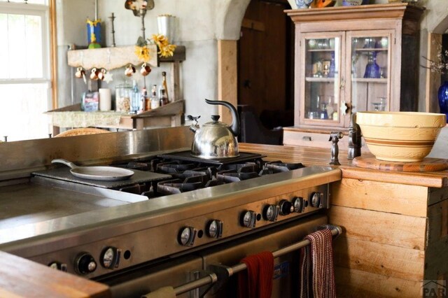 kitchen with arched walkways, cooktop, and glass insert cabinets