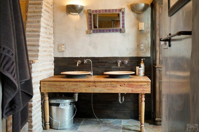 full bath featuring stone finish floor and double sink