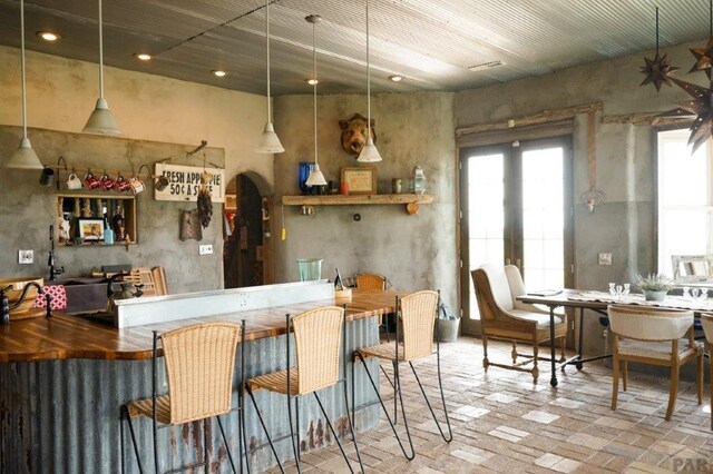 bar with a healthy amount of sunlight, brick floor, and pendant lighting