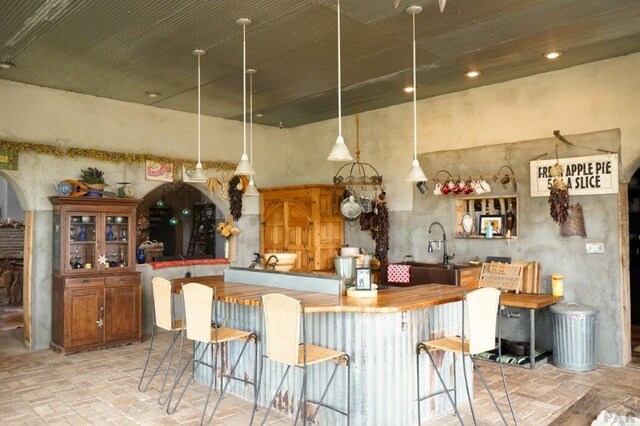 kitchen featuring a towering ceiling, brick floor, a kitchen bar, and arched walkways