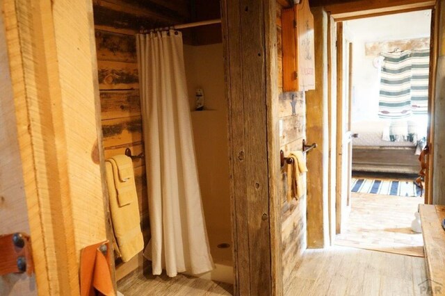 interior space with wood finished floors and a shower with shower curtain