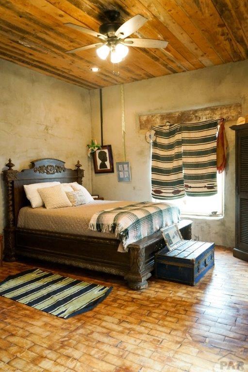 bedroom with brick floor, wooden ceiling, and a ceiling fan