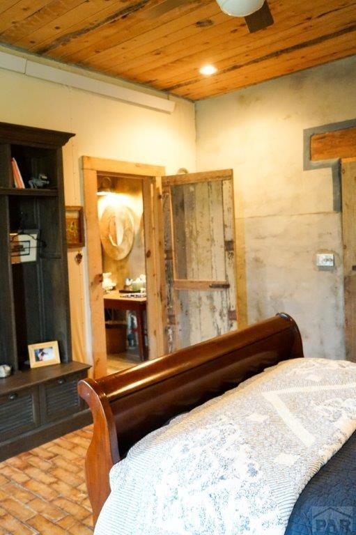 bedroom with wooden ceiling and brick floor